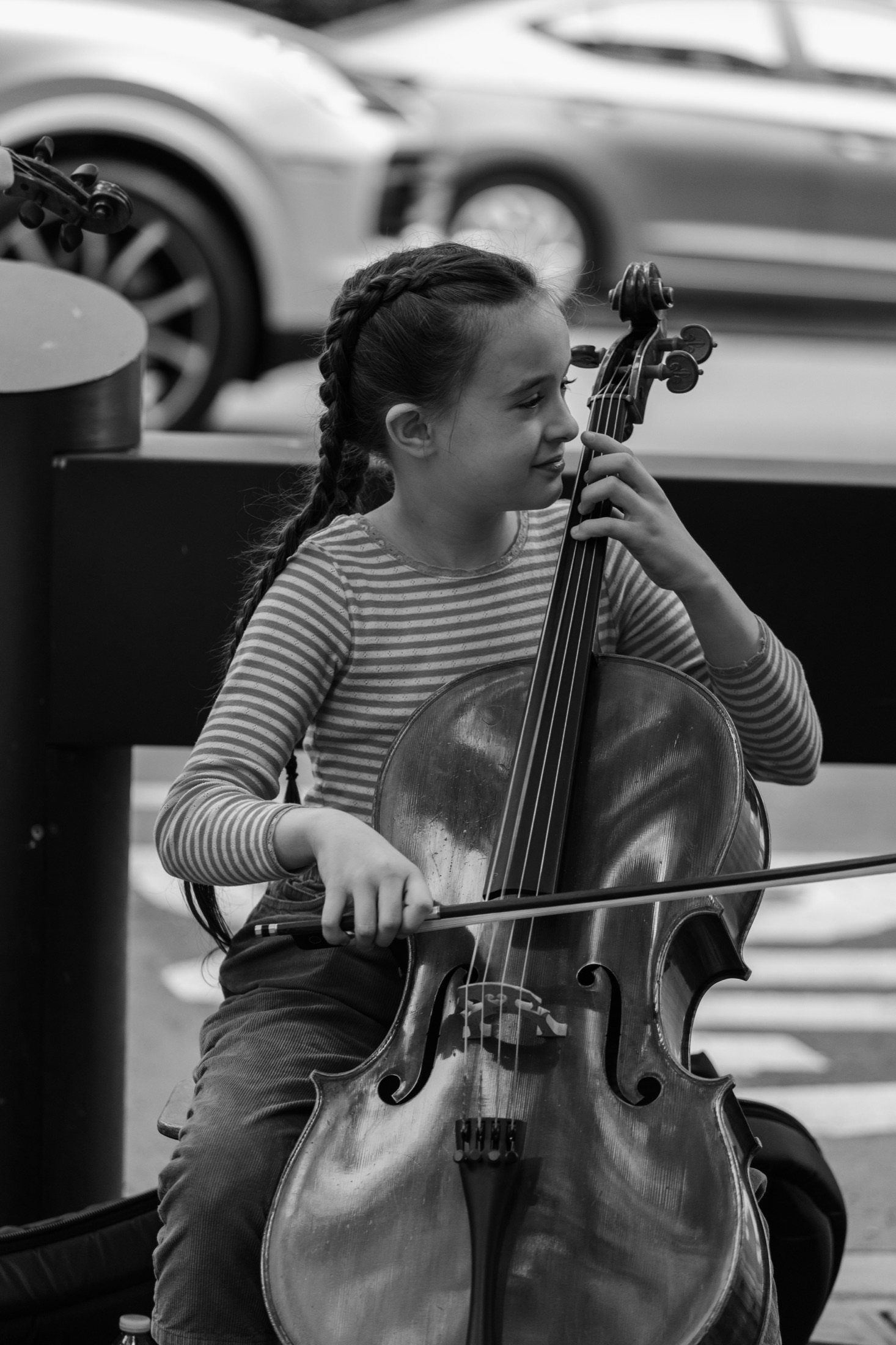 Young girl playing cello on a New York City street, candid black and white — street photography by Brian Mullin