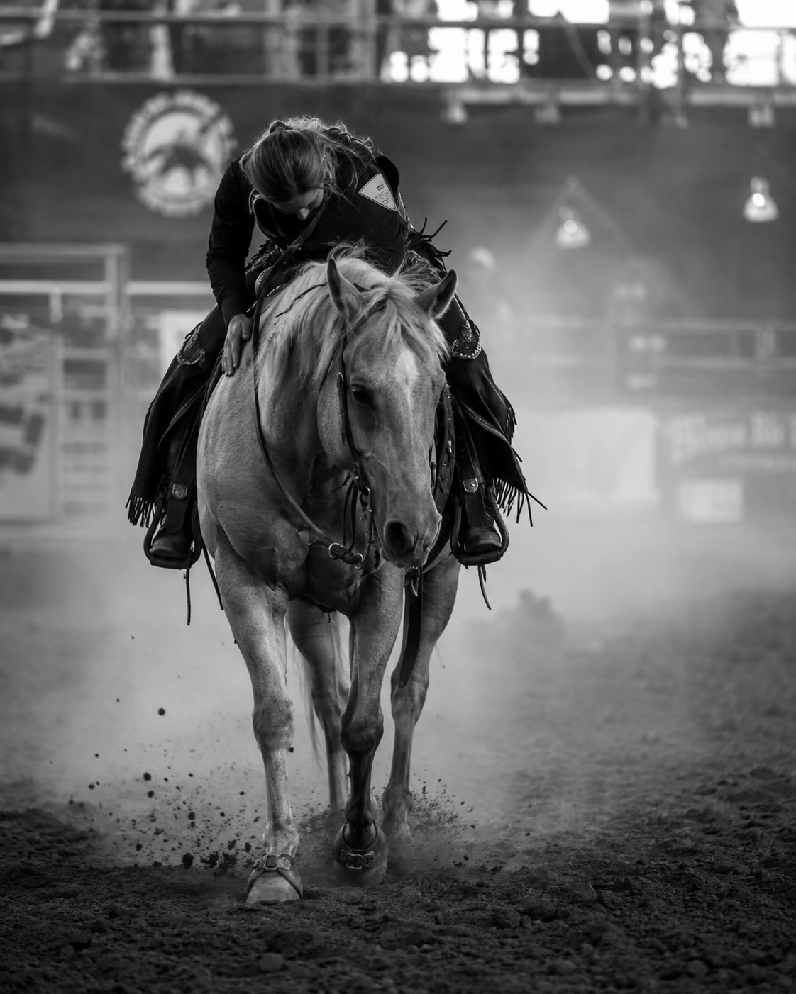Barrel racer on a palomino driving head-on through the dust — black-and-white rodeo photography by Brian Mullin, Pause Studios.