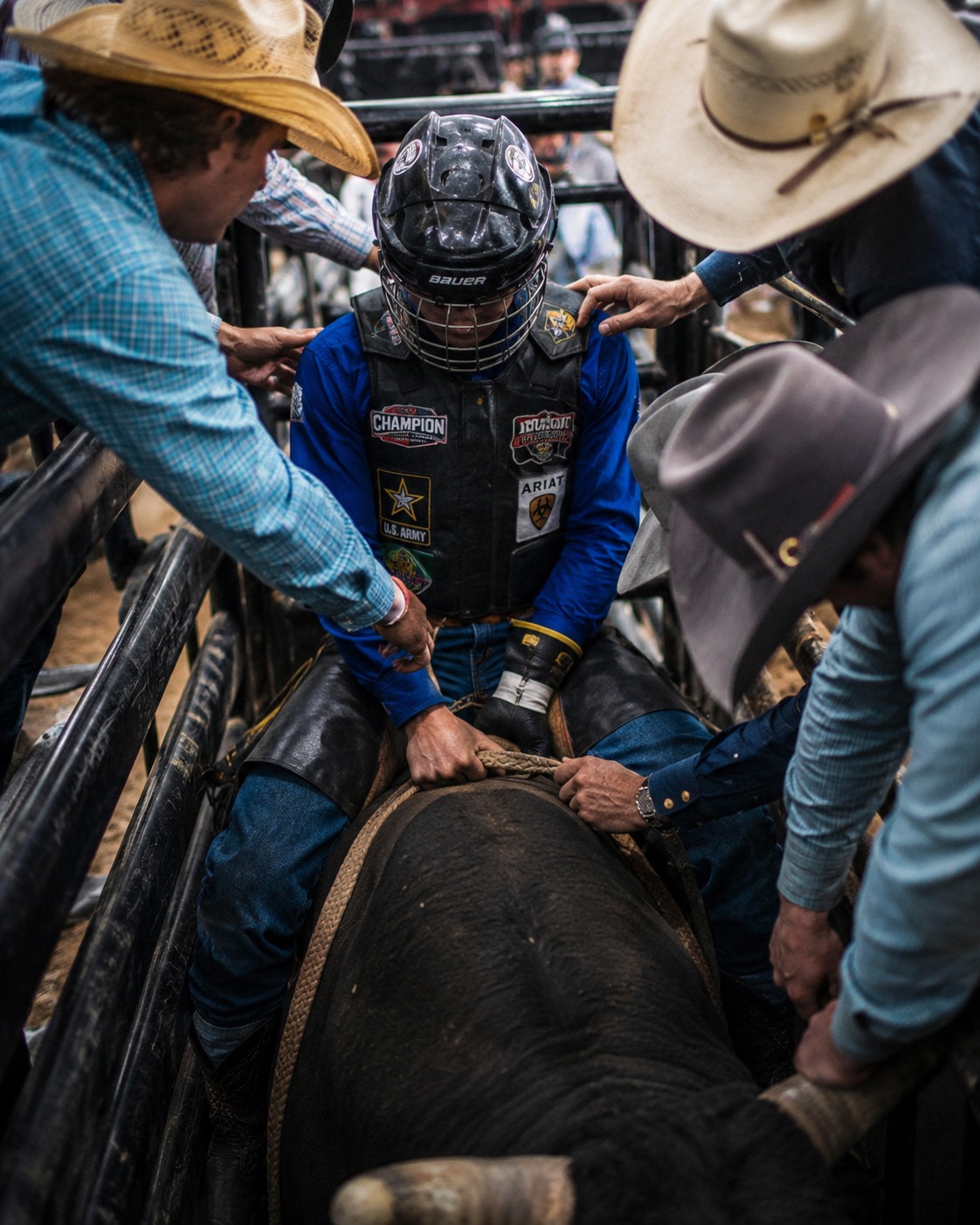 Bull rider being helped onto the bull in the chute, overhead view — rodeo photography by Brian Mullin, Pause Studios.