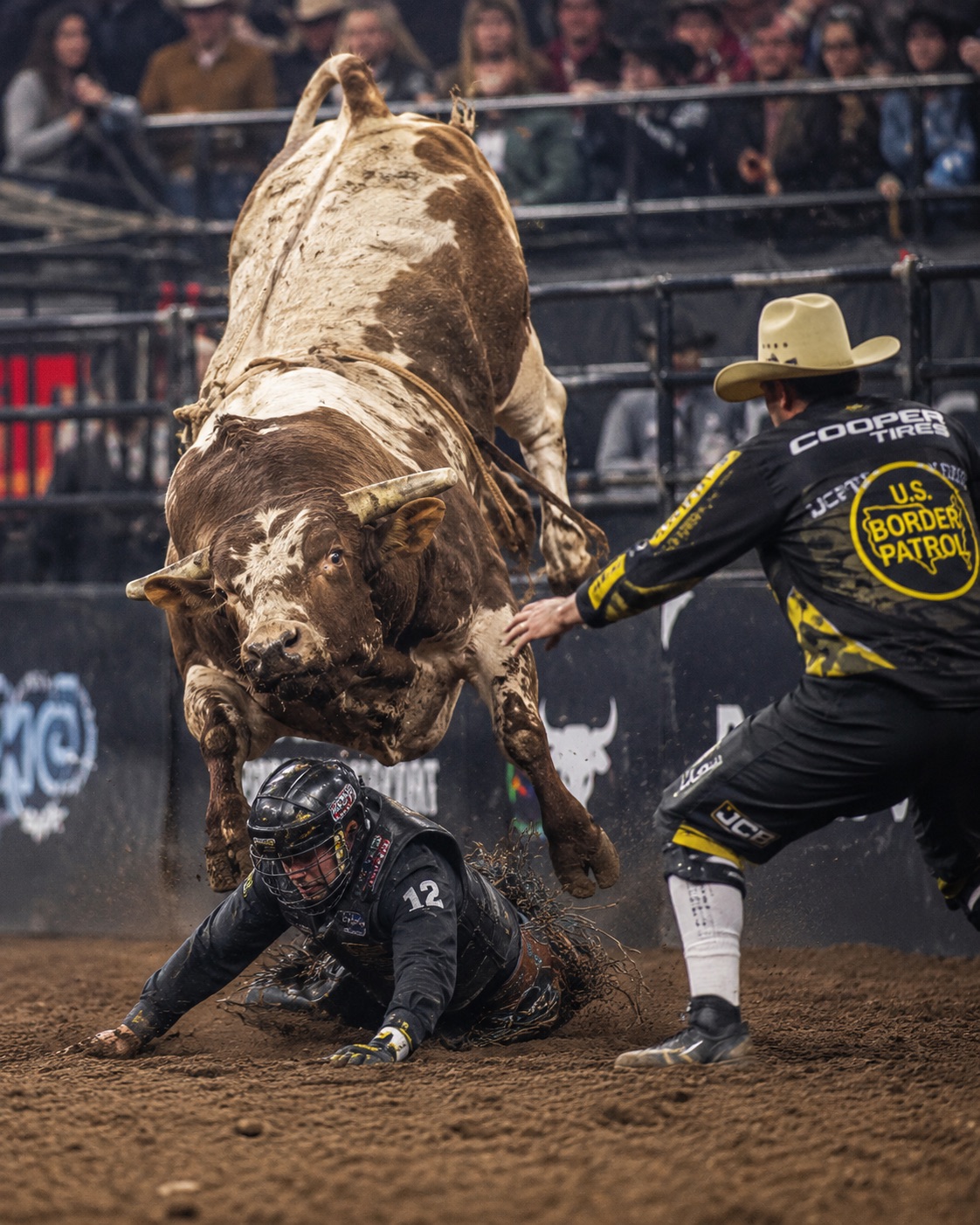 Bullfighter stepping in as a bull turns on a downed rider in front of the crowd — rodeo photography by Brian Mullin, Pause Studios.