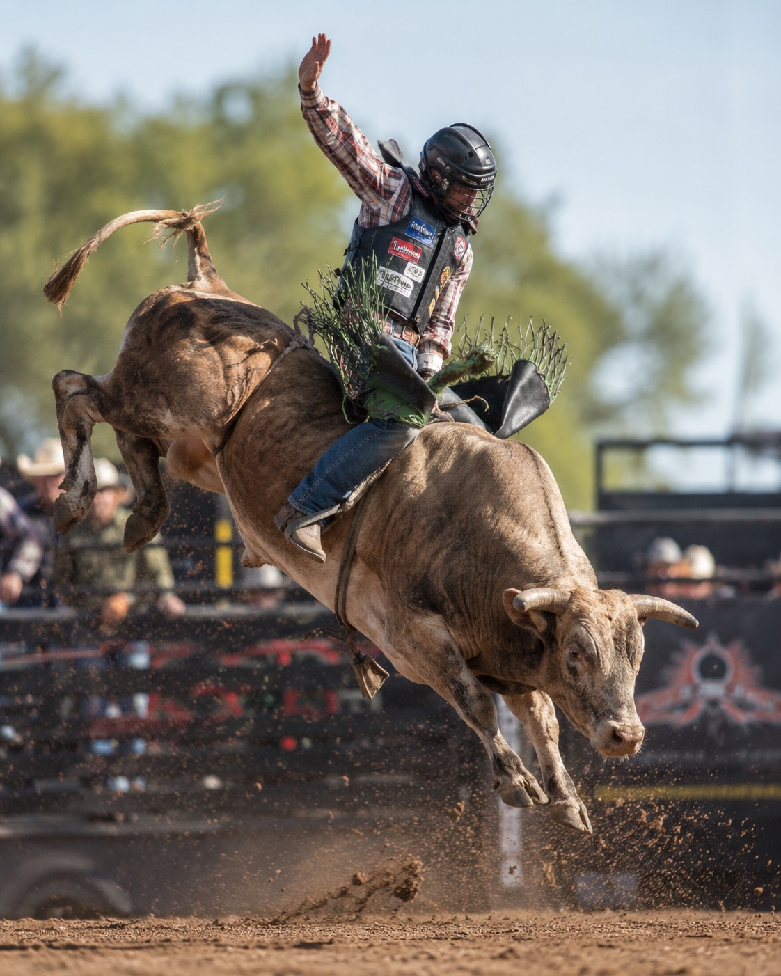 Bull rider holding a ride with one arm raised in daylight — rodeo photography by Brian Mullin, Pause Studios.