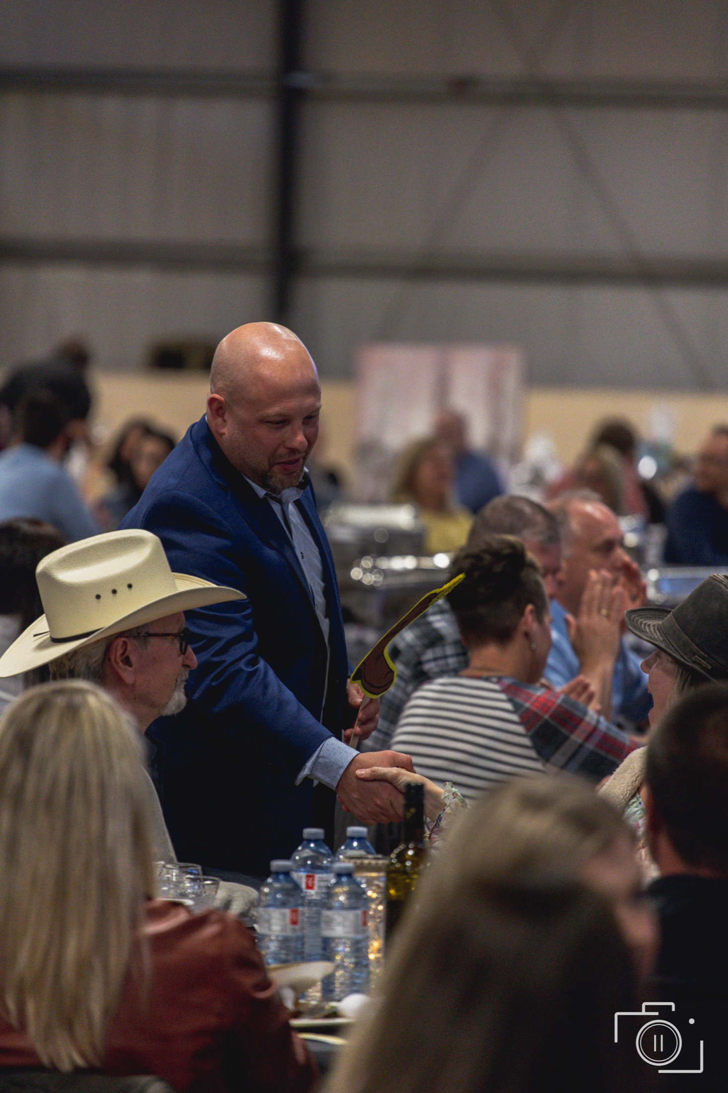 Presenter working the room at a corporate gala, engaged audience at round tables — event photography by Brian Mullin