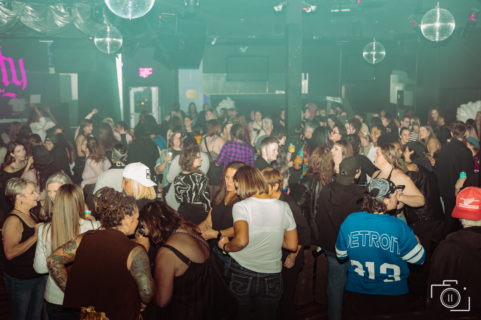 Crowd at a Detroit live event under teal disco lighting