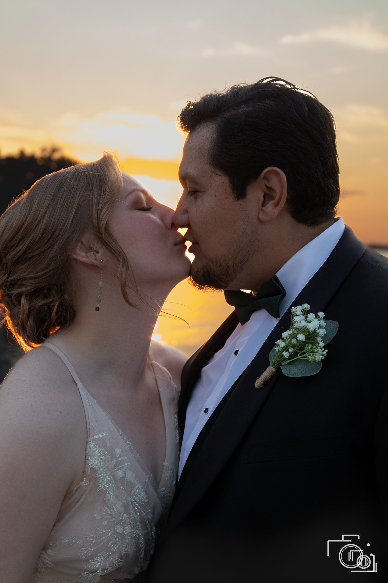Bride and groom share a quiet kiss at golden hour by the water. Candid wedding photography by Brian Mullin, Pause Studios.