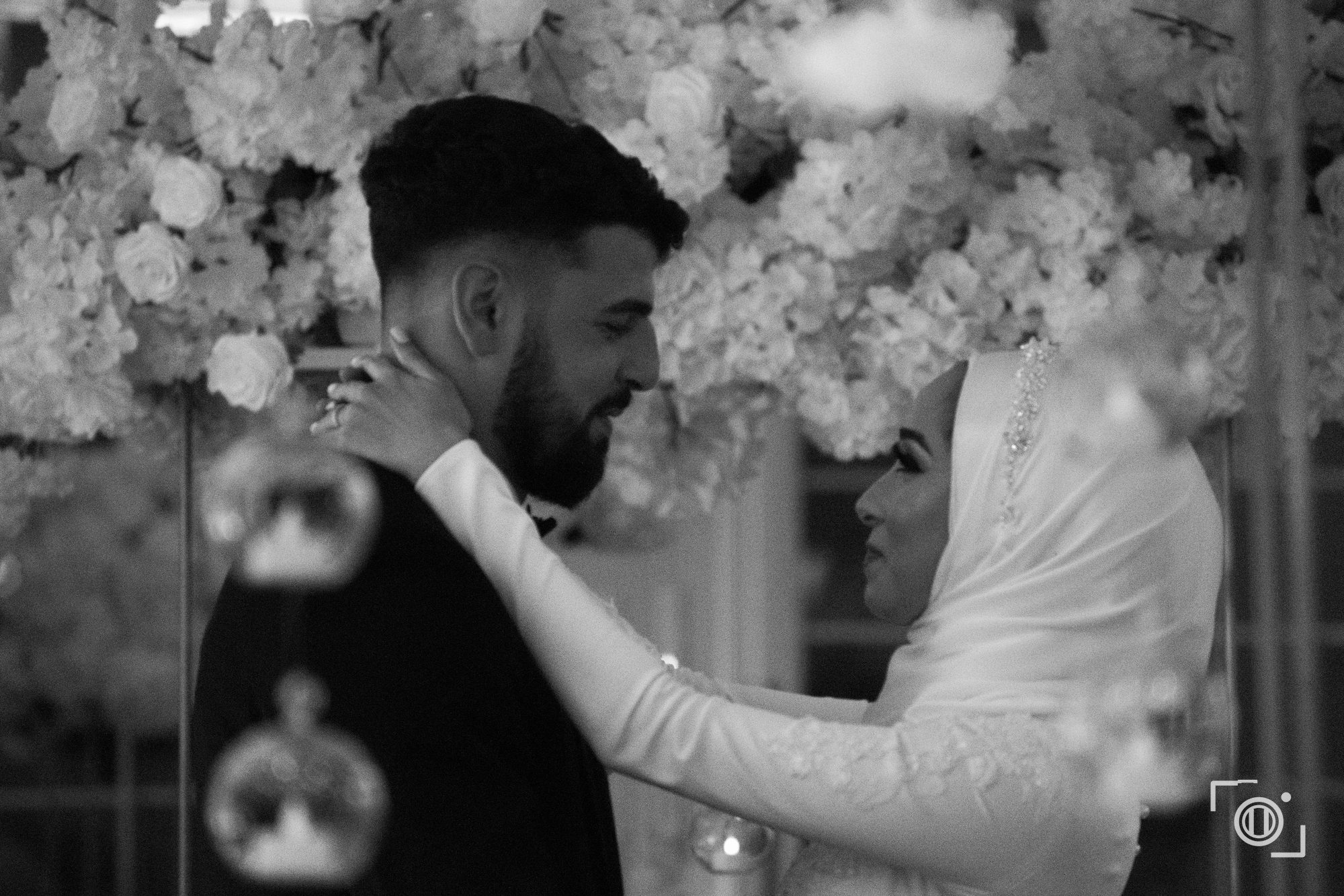 Black and white embrace by the floral wall. Intimate wedding coverage by Brian Mullin, Pause Studios.