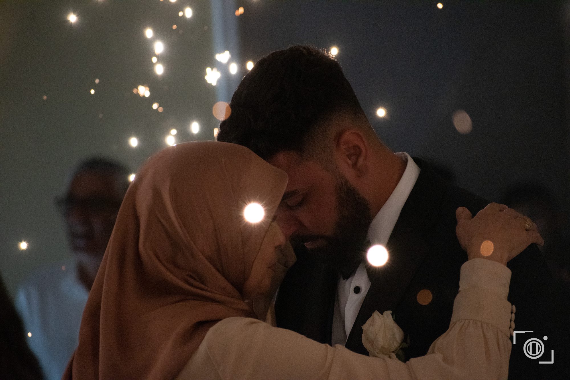 Couple embrace surrounded by sparkler light at the end of the night. Intimate wedding photography, Pause Studios.