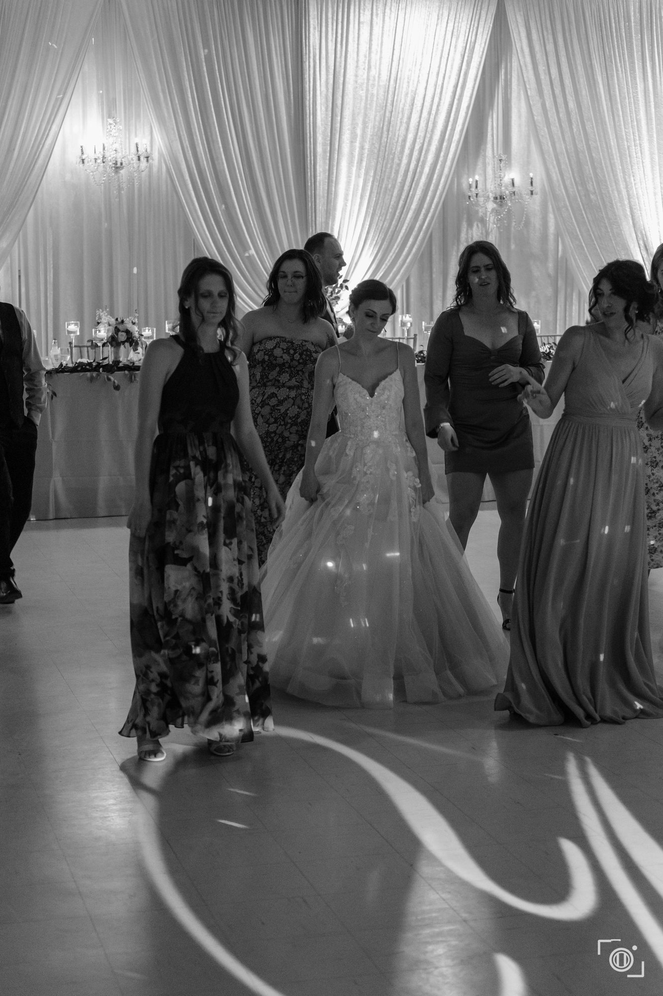 Bride dancing, her gown in motion under the lights, black and white. Wedding photography, Pause Studios.