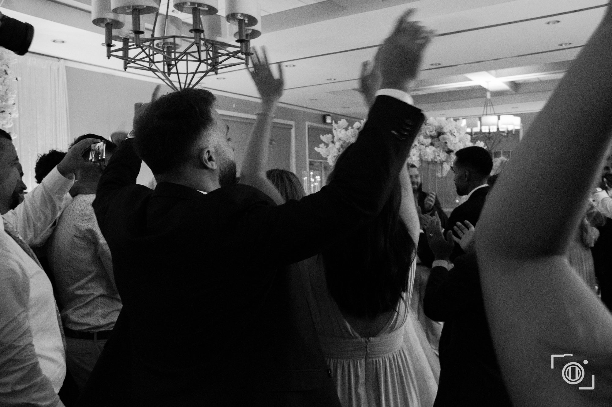Hands in the air on the dance floor, black and white energy. Wedding reception photography, Pause Studios.
